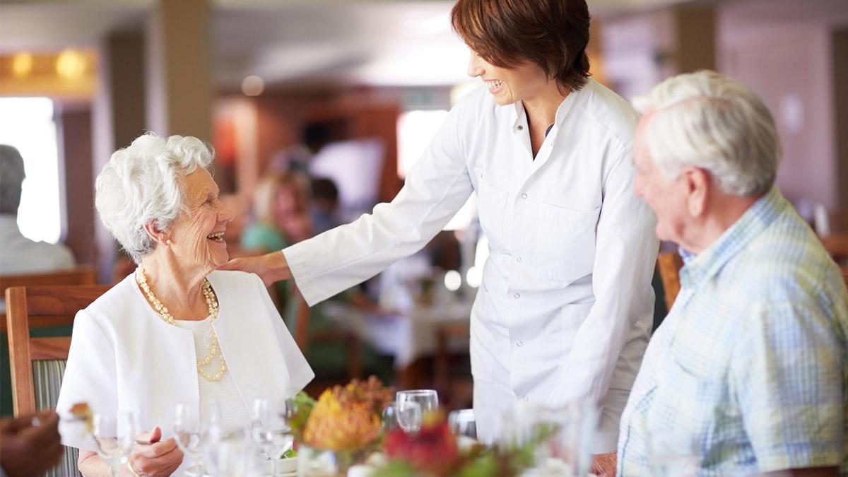 Senior couple and nurse laughing
