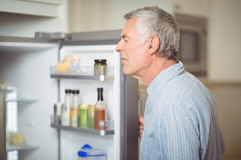 Older man looking for food in fridge