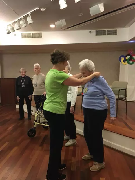 Staff at senior home giving resident a medal